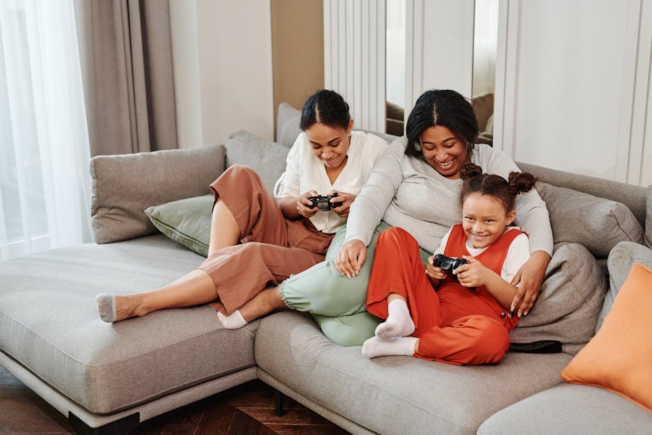 A joyful family moment as mother and daughters play video games together on the couch.