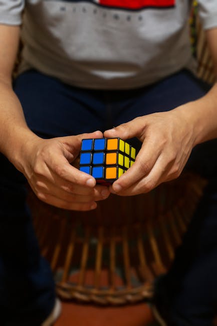 Close-up of hands solving a colorful Rubik's Cube, showcasing focus and problem-solving skills.